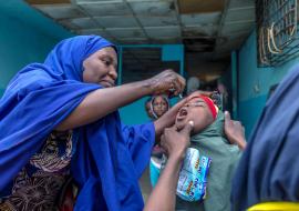 Un vaccinateur fournit à une jeune fille un vaccin oral contre la polio dans l'État de Kano, au Nigeria, en 2020