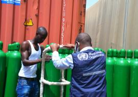 WHO staff supervising the offloading of oxygen cylinders at the Ministry of Health 
