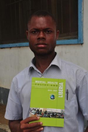 A mental health worker displaying a copy of the Mental Health Policy and Strategic Plan