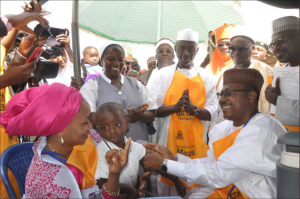 ED NPHCDA Dr Faisal Shuaib vaccinating the child of the Governor of Kaduna state while the Governor’s wife Hajiya Ummi El Rufai looks on.