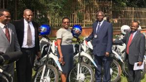 Minister of Health, Dr, Jane Ruth Aceng receives the motorcycles from WHO Acting Rep in Uganda, Dr. Jack Abdoulie as Ministry officials look on