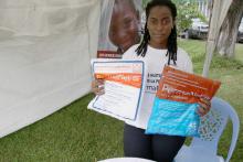 Les moustiquaires imprégnées d'insecticide à longue durée d'actions sont un élément essentiel dans la lutte contre le paludisme et la réduction de la morbidité au sein de la population. Cette jeune femme dit s'engager en utilisant la moustiquaire pour zéro palu dans sa famille. OMS/Eugene Kabambi.