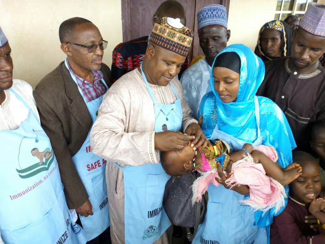 Alhaji Mohammed Abubakar (3rd left) Chairman of Tarmuwa LGA Yobe State immunizing a child during OBR flag off.