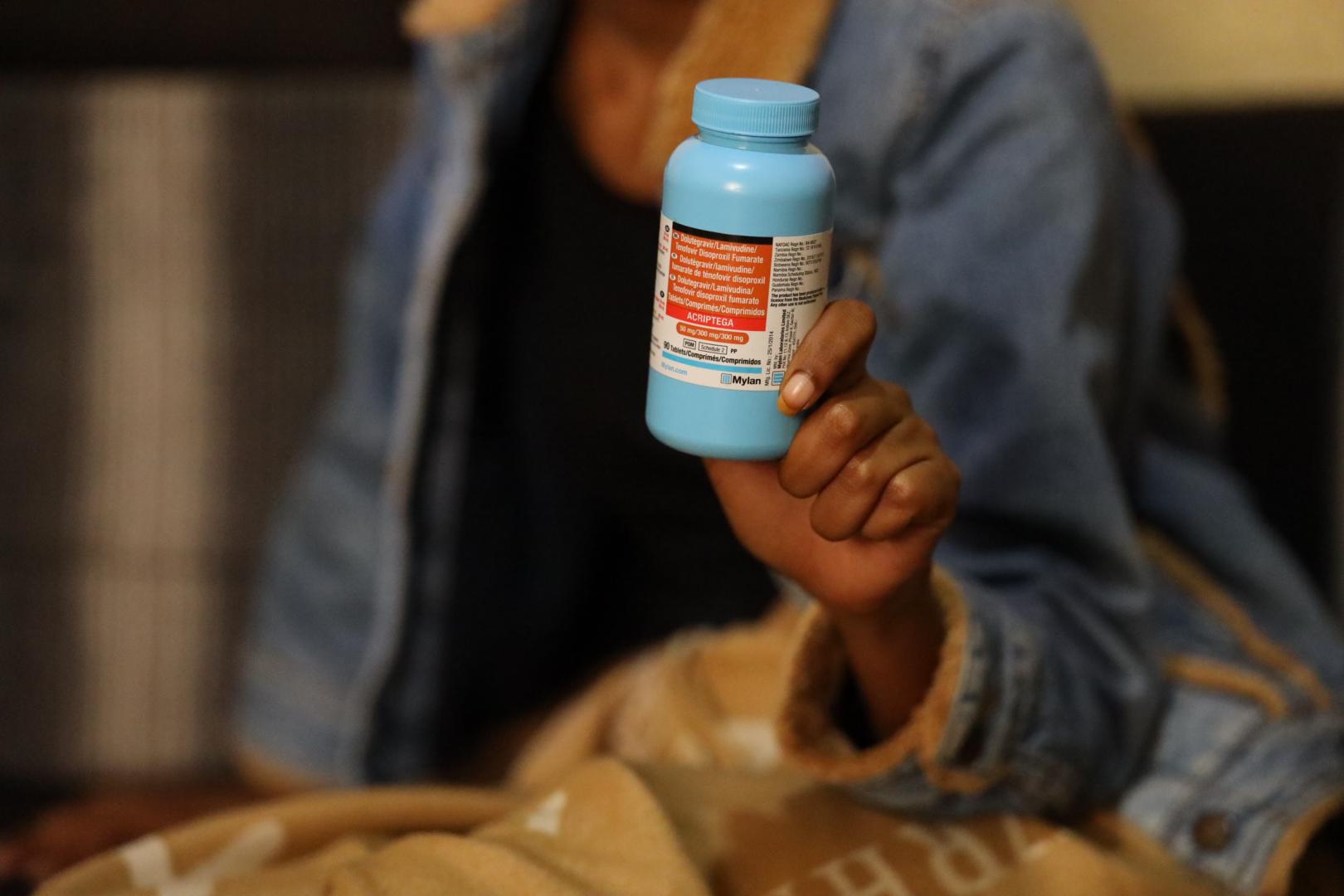 A woman holding a bottle of their prescription pills for HIV