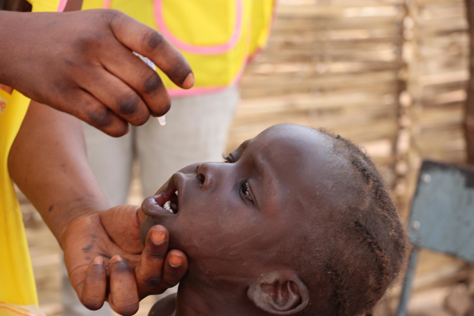 Healthcare workers administering the polio vaccine to a child as part of immunization efforts to protect children from poliovirus.