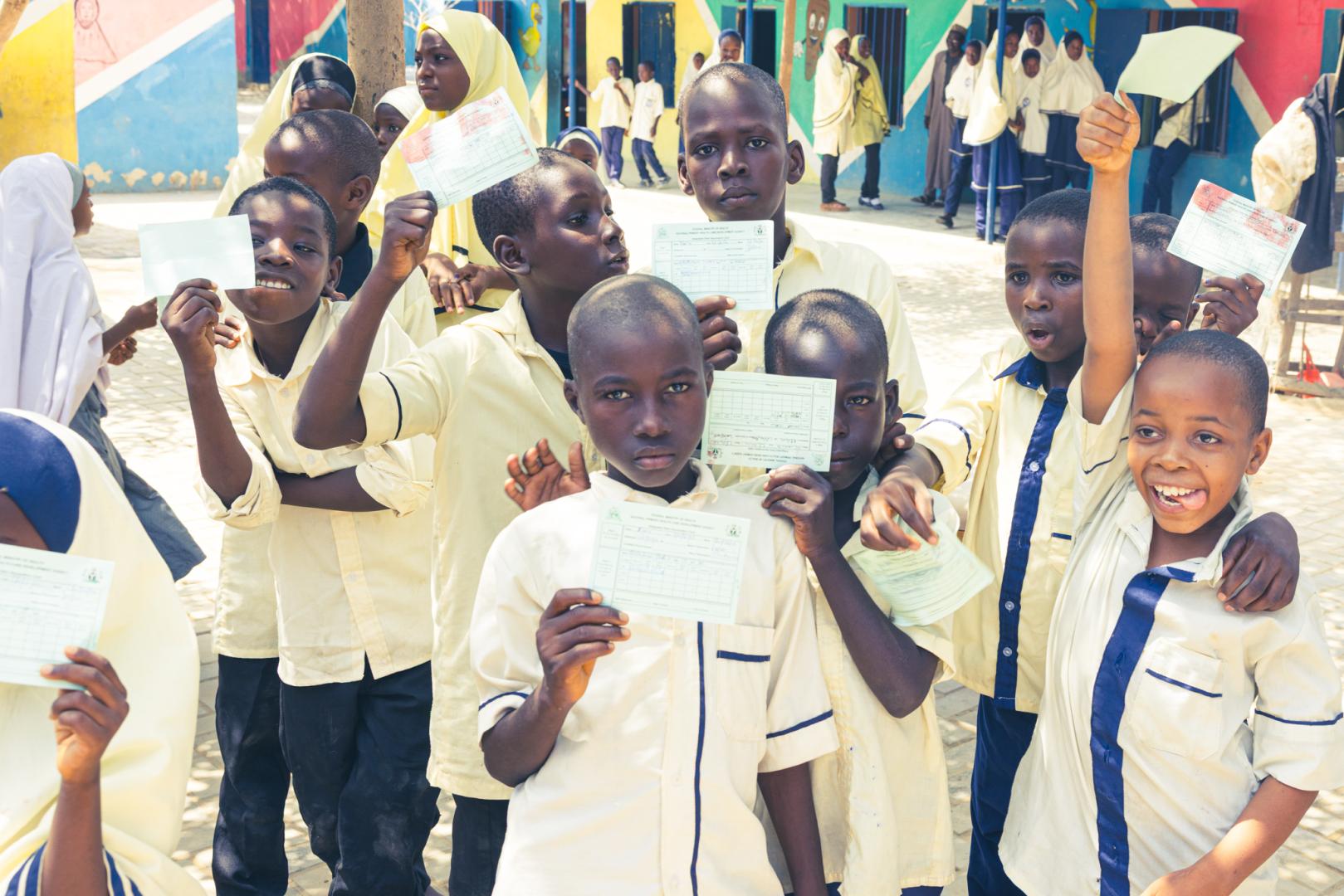 Children showing  off vaccination cards after being vaccinated.