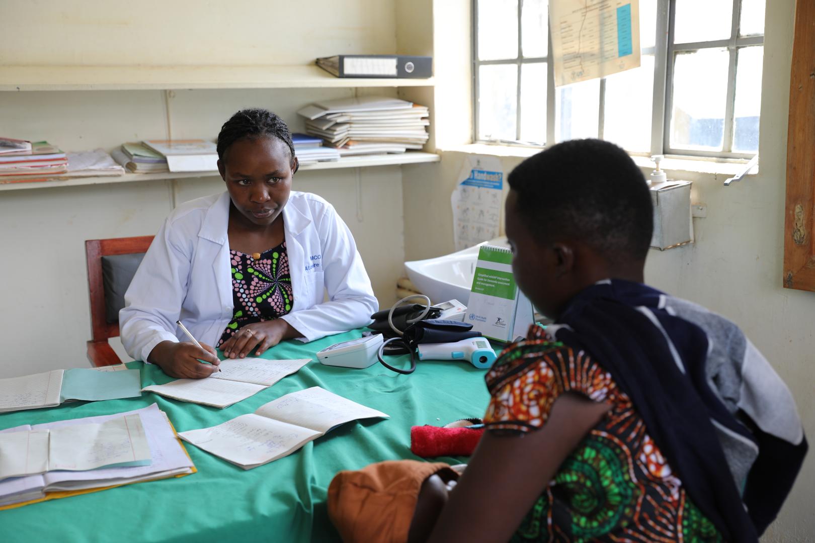Jovita Atuheire a health worker at Maziba Health Center IV interacting with a patient 