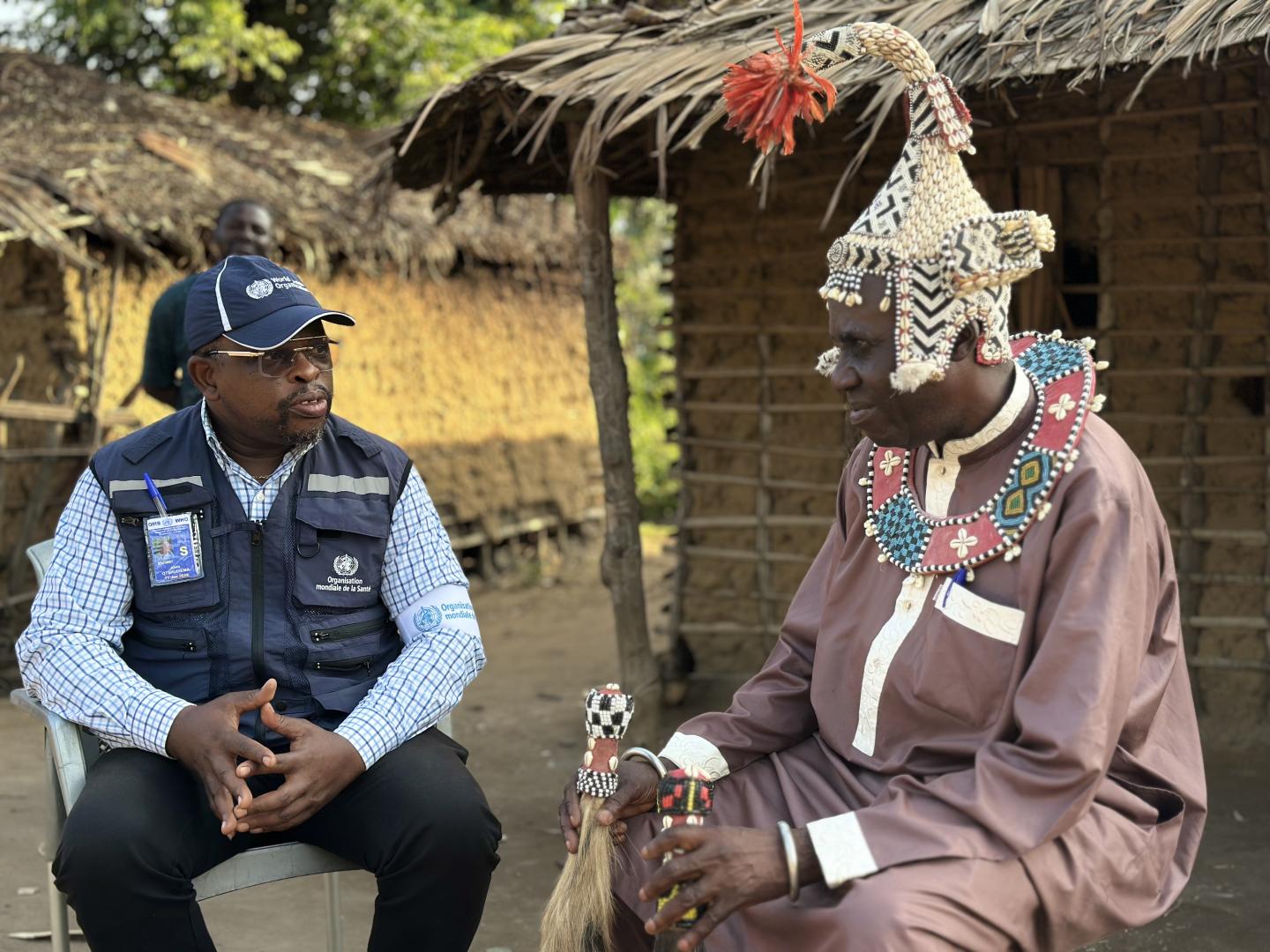 Dr John Otshudiema, épidémiologiste et gestionnaire adjoint de l’incident Ebola pour l’OMS, échange avec le chef coutumier Bidiaka. Ce dernier lui explique comment les rites ancestraux ont contribué à accélérer le contrôle de la maladie à virus Ebola dans la zone de santé de Bulape. Crédit photo : OMS/René Ifono