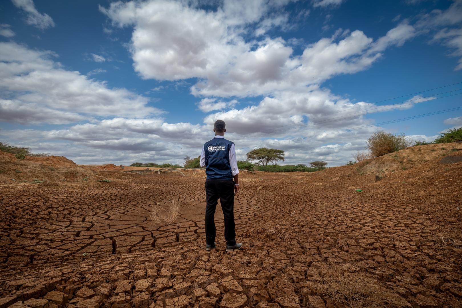 Tillen Oduwo from WHO surveys a dried out river in Tula, Tana River County.