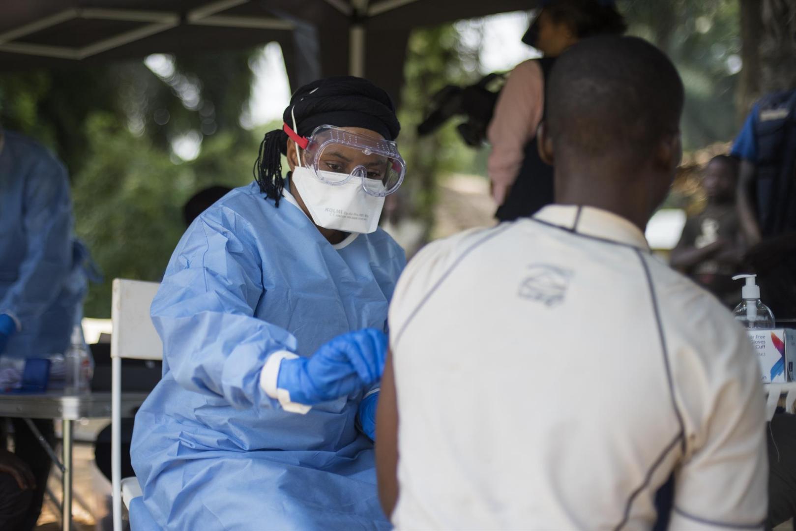 A member of the ring vaccination team vaccinates a man in Bosolo village.