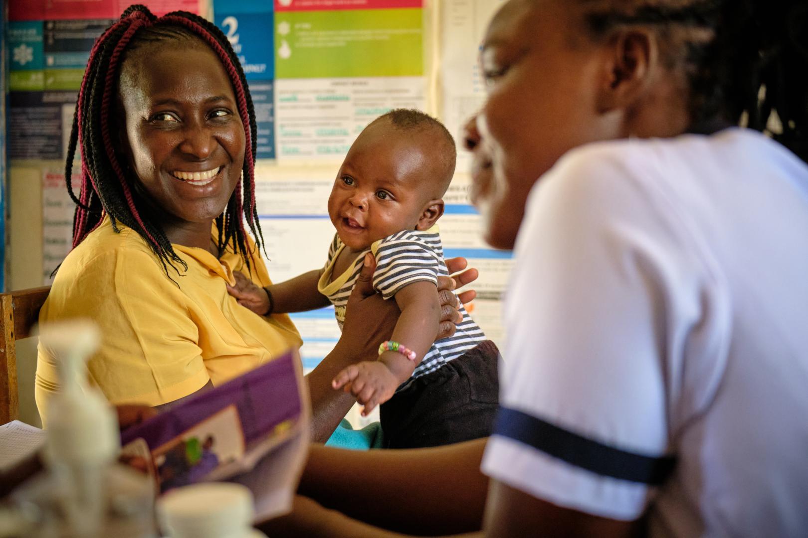A mother holds her baby during a health check at a health facility