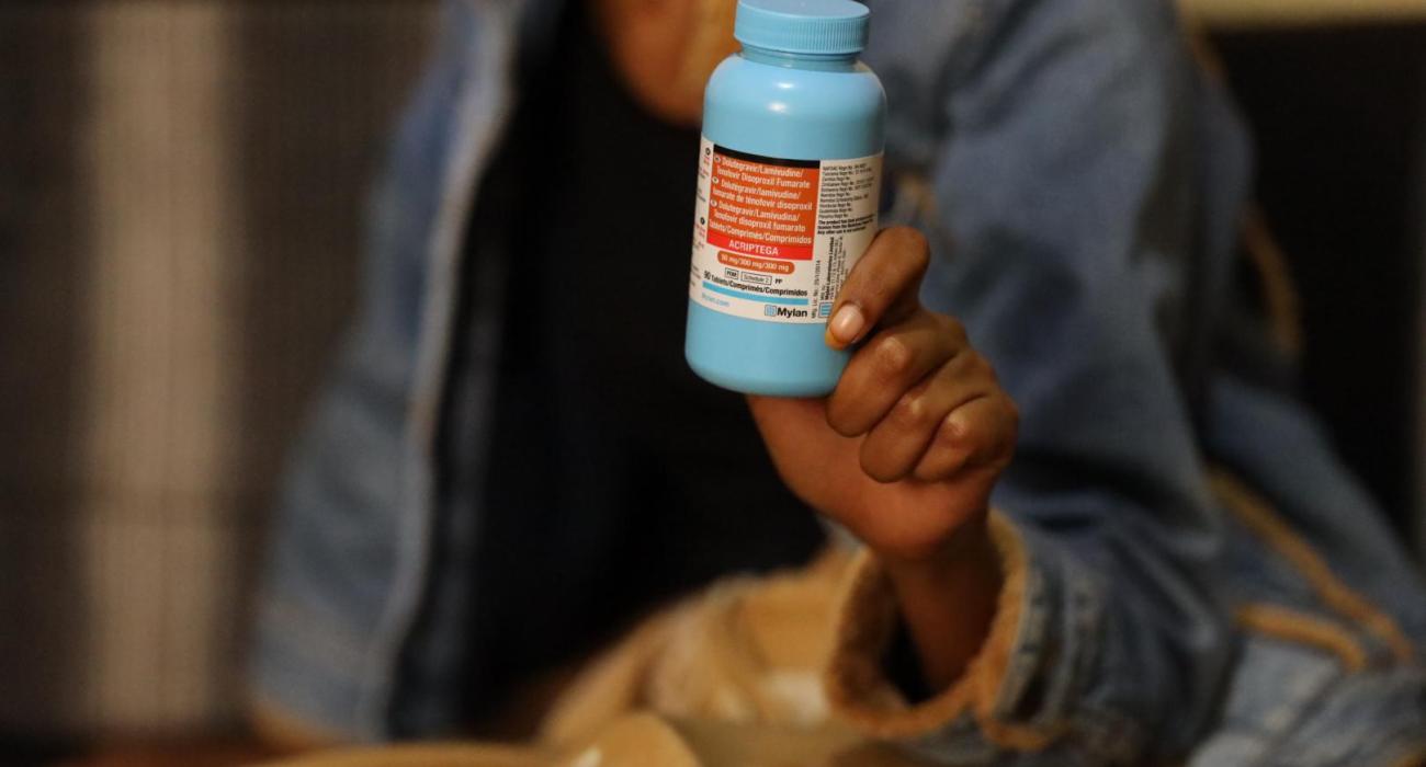 A woman holding a bottle of their prescription pills for HIV