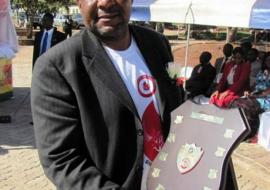 The Headmaster of John Tallach High School, national winners, showing off the shield won by the school