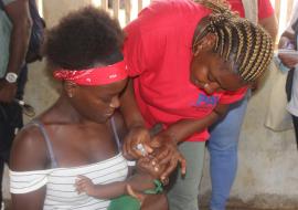 Uma crianca de seis meses recebendo a sua vacina de reforco