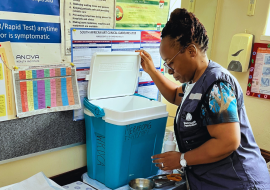 Dr Simangele Mthethwa, WHO South Africa NPO (VPD Surveillance) captured during the 2023 measles vaccination campaign, symbolizing determination and responsibility as she inspects vaccines at a vaccination center. Her earnest expression reflects a commitment to eliminating measles in South Africa.