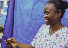 Nyanjikua Foday- Vaccinator at Dupo Road Health centre in Montserrado smiles after receiving a mobile money notification. 