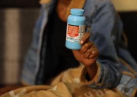 A woman holding a bottle of their prescription pills for HIV