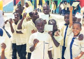 Children showing  off vaccination cards after being vaccinated.
