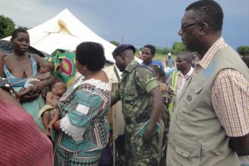 The Honorable Minister Dr Jean Kalilani comforting a twin child listens to the mother of the twins living in one of the camps in Chikwawa districts while Dr Nyarko (far right) in khaki WHO field coat looks on WHO Malawi photo