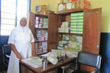 A nurse at Gwata Dispensary displaying the stock of medicines and supplies.
