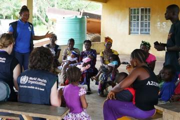 Ebola outbreak in Sierra Leone: WHO staff talking to mothers in Sierra Leone on getting children to health care.