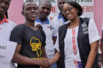 Dr Moeti shakes the hand of Sherrie Bangura (black t-shirt), Ebola survivor and founder of 'The Rescue Team', a network of Ebola survivors in Port Loko district. WHO / P. Desloovere