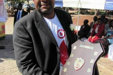 The Headmaster of John Tallach High School, national winners, showing off the shield won by the school