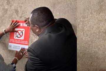 01 La Ministre ivoirienne de la sante, Dr Raymonde Goudou Coffie, aidee par le Vice Gouverneur du district d Abidjan, a affiche les 1er panneaux d interdiction de fumer sur les murs de l hotel du district