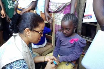 Representante da OMS marcando o dedo da criança vacinada