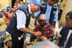 Dr Alemu administering oral polio vaccine to a child in a Borno IDP camp
