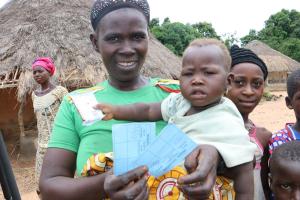 A woman and her child in Yendeya Village displaying her child's measles vaccination card. Photo credit: WHO/S. Gborie