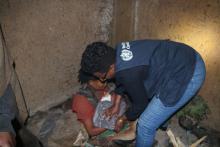 WHO staff helps mother wrap baby in warm blanket at Gedeb IDP site