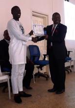 Dr. Moses Jeuronlon, WHO Technical Officer presenting a certificate of recognition to one of  the best Counties Health Officer at the end of the Annual National Health Review Conference