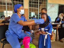 A nurse administers medicine to a local student during the MDA campaign in the North Bank Region